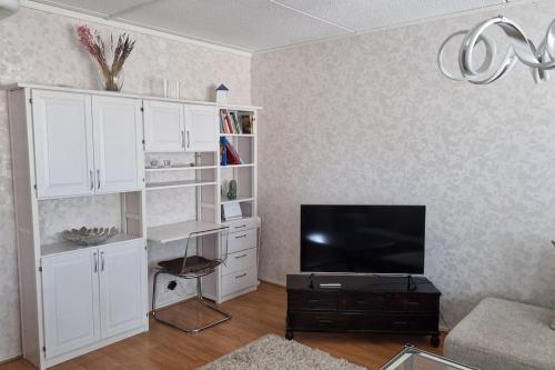 a living room with a tv and white cabinets at Lovely apartment in Itäsatama in Hanko