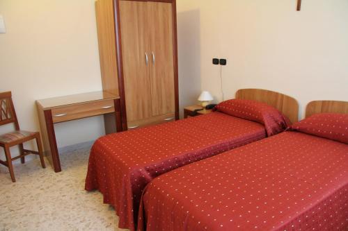 a hotel room with two beds and a table and chair at Hotel La Casa Del Pellegrino in SantʼAnastasia