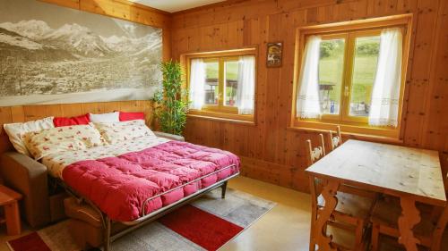 um quarto com uma cama, uma mesa e janelas em Casa Agnese e Rino em Bormio