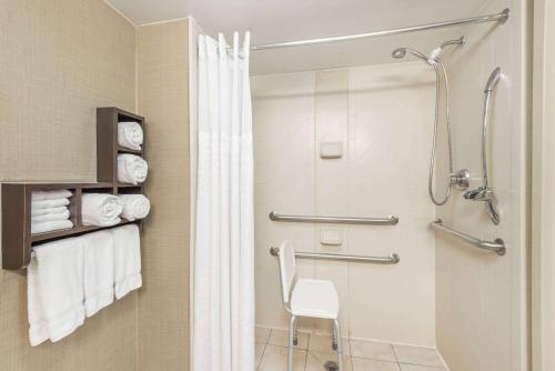 a bathroom with a shower and a white chair at Wingate by Wyndham Springfield in Springfield