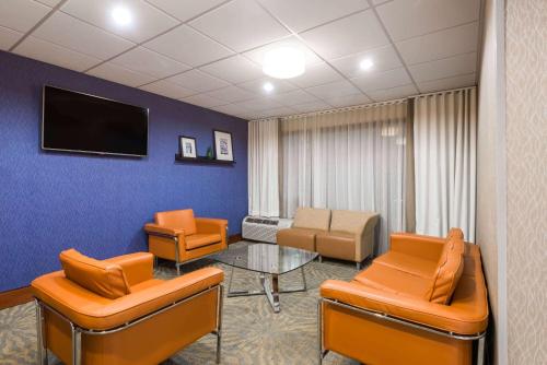 a waiting room with orange chairs and a tv at Wingate by Wyndham Springfield in Springfield