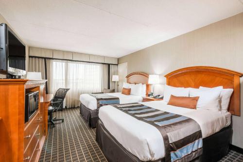 a hotel room with two beds and a flat screen tv at Wingate by Wyndham Springfield in Springfield