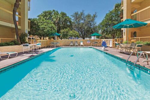 una gran piscina con sillas y sombrillas en Super 8 by Wyndham San Antonio Near SeaWorld Ingram Park, en San Antonio