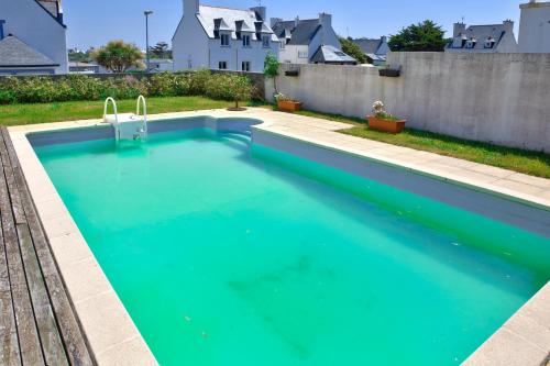 une piscine avec de l'eau bleue dans une cour arrière dans l'établissement Echappee relaxante au bord de l ocean a Penmarch, à Penmarcʼh