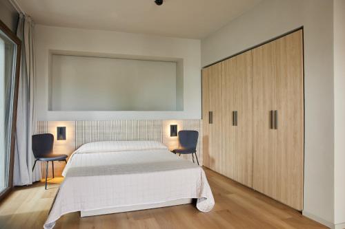 a bedroom with a large white bed and two chairs at Mima Aparthotel Boutique & Spa in Milano Marittima