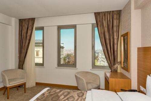 1 dormitorio con 1 cama, 2 sillas y ventanas en Mıen Hotels en Estambul