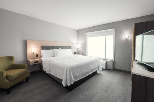 a bedroom with a bed and a chair and a window at Home2 Suites By Hilton Quebec City in Quebec City