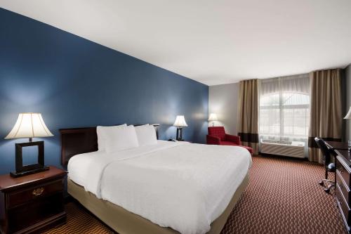 a hotel room with a large bed and a red chair at Quality Inn & Suites Oklahoma City North in Edmond