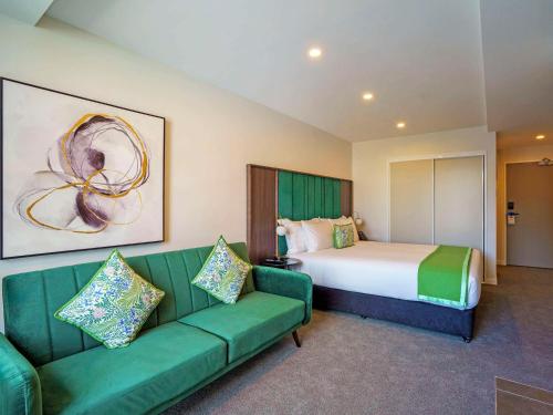 a hotel room with a bed and a green couch at The Sebel Wellington Thorndon in Wellington