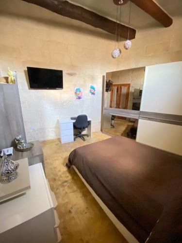 a bedroom with a bed and a desk and a tv at Vintage Farmhouse in Qormi