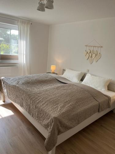 a white bedroom with a large bed and a window at Ferienwohnung II im idyllischen Gulfhof in Krummhörn