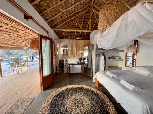 a bedroom with a bed and a room with a table at LA DUNE DES SONGES in Anakao