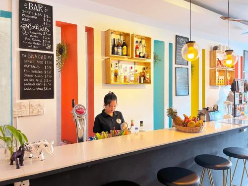 a woman sitting at a counter in a restaurant at THE PLACE Hostel & Pool Bar in Siem Reap