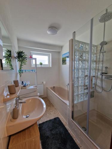 a bathroom with a sink and a shower and a tub at Ferienwohnung Starennest mit direktem Harzblick in Bad Lauterberg