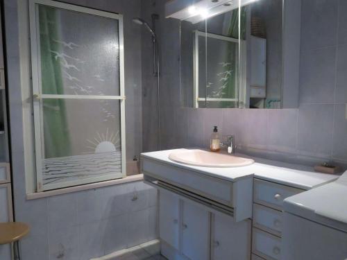 ein weißes Badezimmer mit Waschbecken und Fenster in der Unterkunft Maison bretonne avec jardin à 50m de la baie Ste Anne - FR-1-368-252 in Trégastel