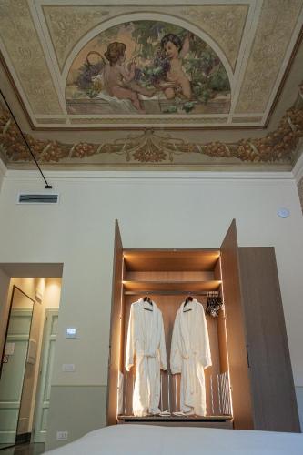 a display case with two white clothes in a room at Grand Universe La Residenza in Lucca
