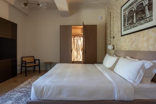 a bedroom with a large white bed and a chair at Grand Universe La Residenza in Lucca