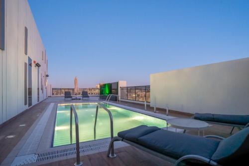 AKASIYA HOTEL في الدوحة: مسبح مع كنب وطاولة