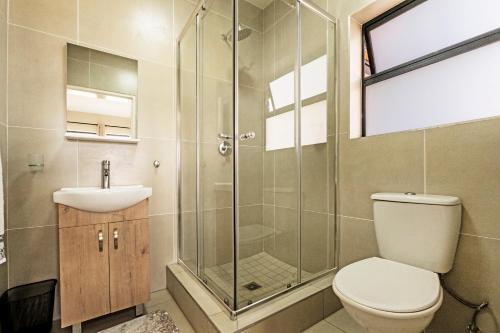 a bathroom with a shower and a toilet and a sink at Airport Heights in Boksburg