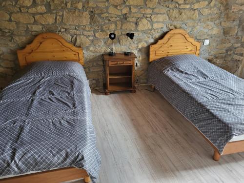 two beds in a room with a stone wall at KERHAM in Plouay
