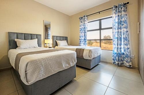 two beds in a room with a window at Airport Heights in Boksburg