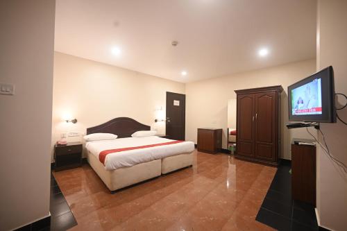 a bedroom with a bed and a flat screen tv at Hotel Bhagavath Gardens in Chengannūr