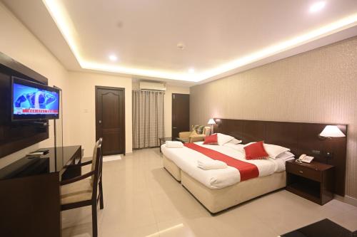 a hotel room with a bed and a flat screen tv at Hotel Bhagavath Gardens in Chengannūr