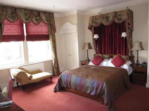 a bedroom with a large bed with red curtains at Woodlands Hotel in Spalding