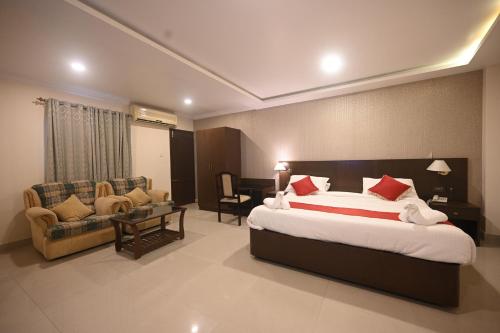 1 dormitorio con 1 cama grande y sala de estar en Hotel Bhagavath Gardens, en Chengannūr