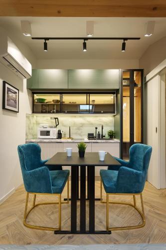 a dining room with a table and two blue chairs at IDEA LUX Apartmani Kragujevac in Kragujevac