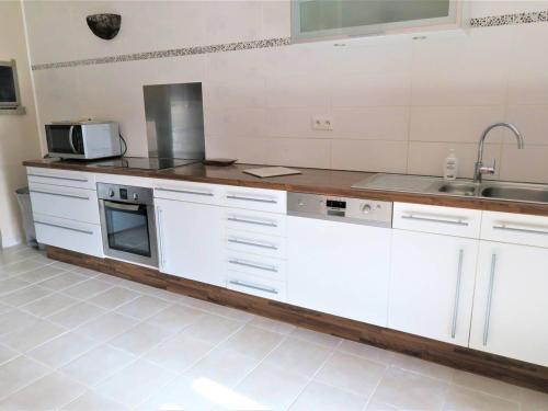 une cuisine avec des armoires blanches et un évier dans l'établissement Maison bretonne avec jardin clos, centre Perros-Guirec, proche plage et commerces - FR-1-368-285, à Perros-Guirec