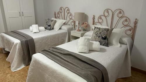 a bedroom with two beds with white sheets and pillows at Casa Rural Las Camelias in Herrera del Duque