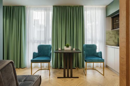 a living room with green curtains and a table and chairs at IDEA LUX Apartmani Kragujevac in Kragujevac