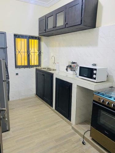 cocina con encimera y microondas en 2 Chambres salon meublés, en Cotonou