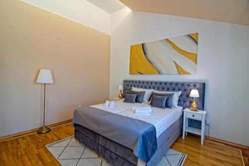 a bedroom with a bed and a painting on the wall at Stross Apartments & Rooms in Osijek