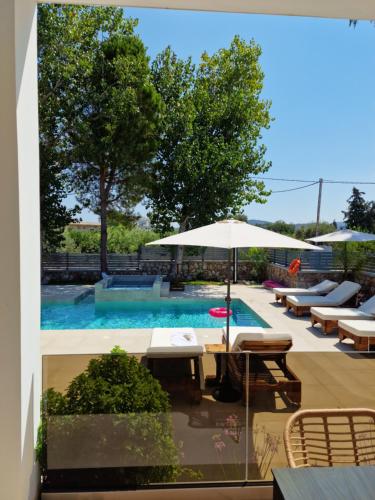 una piscina con tavoli, sedie e ombrellone di Luxury Villa Anemone with private pool a Pastida