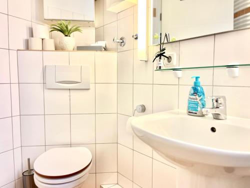 a white bathroom with a toilet and a sink at Wohlfühl Strand Wohnung 'Mein Ankerplatz' in Lübeck
