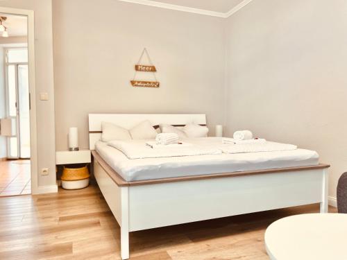 Cama blanca en habitación blanca con marco de cama blanco en Wohlfühl Strand Wohnung 'Mein Ankerplatz' en Lübeck