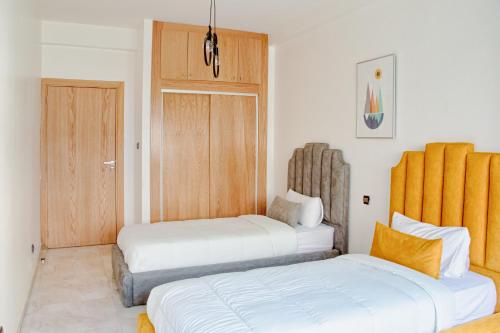 1 Schlafzimmer mit 2 Betten und einer Holztür in der Unterkunft Luxury 3 Bedroom Apartment in the Heart of Agdal Renovated Jan 2025 in Rabat