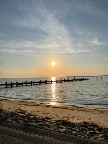 a beach with the sun setting over the water at Wohlfühl Strand Wohnung 'Mein Ankerplatz' in Lübeck