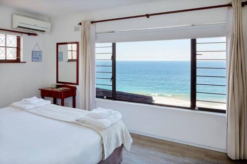 a bedroom with a large window with a view of the ocean at Garvies Surf house in Durban