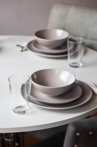 a table with three plates and glasses on it at Luxe Cosy&Spacious 2 Bed House - Super Fast Wi-Fi & Private Parking Near GLO Airport & Cheltenham Racecourse in Churchdown