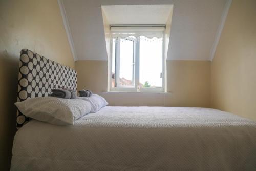 a bedroom with a large bed with a window at Luxe Cosy&Spacious 2 Bed House - Super Fast Wi-Fi & Private Parking Near GLO Airport & Cheltenham Racecourse in Churchdown