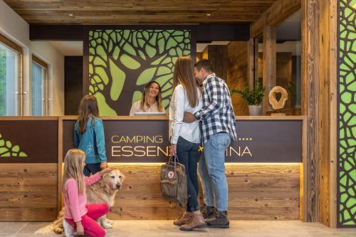 a group of people standing in front of a counter with a dog at Camping Essenza Alpina in Folgaria