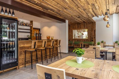 a restaurant with wooden ceilings and a bar with stools at Camping Essenza Alpina in Folgaria