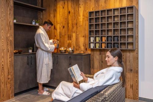 a woman sitting in a chair in a spa with a man standing at Camping Essenza Alpina in Folgaria