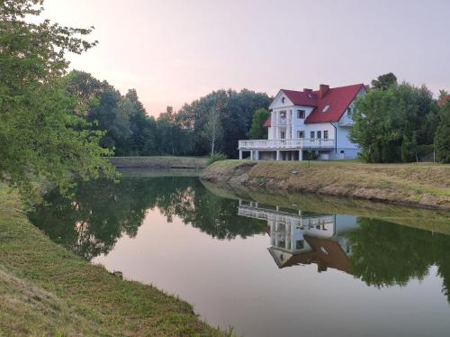 una casa seduta sul fianco di un fiume di Willa Tonkiele - Dom z Jacuzzi i Sauną na wyłączność a Tonkiele