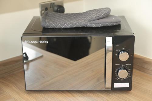 a pillow is sitting on top of a microwave at Luxe Cosy&Spacious 2 Bed House - Super Fast Wi-Fi & Private Parking Near GLO Airport & Cheltenham Racecourse in Churchdown