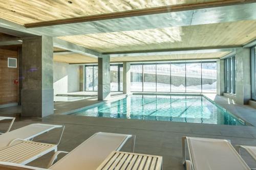 - une grande piscine avec des chaises dans une maison dans l'établissement Appartement Haute gamme ski aux pieds, piscine, sauna., à Bourg-Saint-Maurice