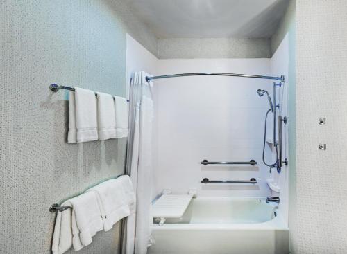 ein Badezimmer mit einer Dusche, einer Badewanne und Handtüchern in der Unterkunft Holiday Inn Express & Suites - Coffeyville, an IHG Hotel in Coffeyville